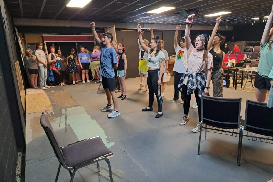 Performers rehearsing with raised arms, simulating excitement over royal ball invitations.