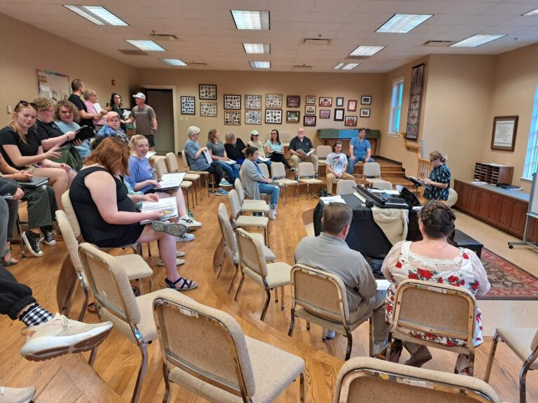 Cast members chatting and preparing, scripts in hand, on the first day of rehearsals