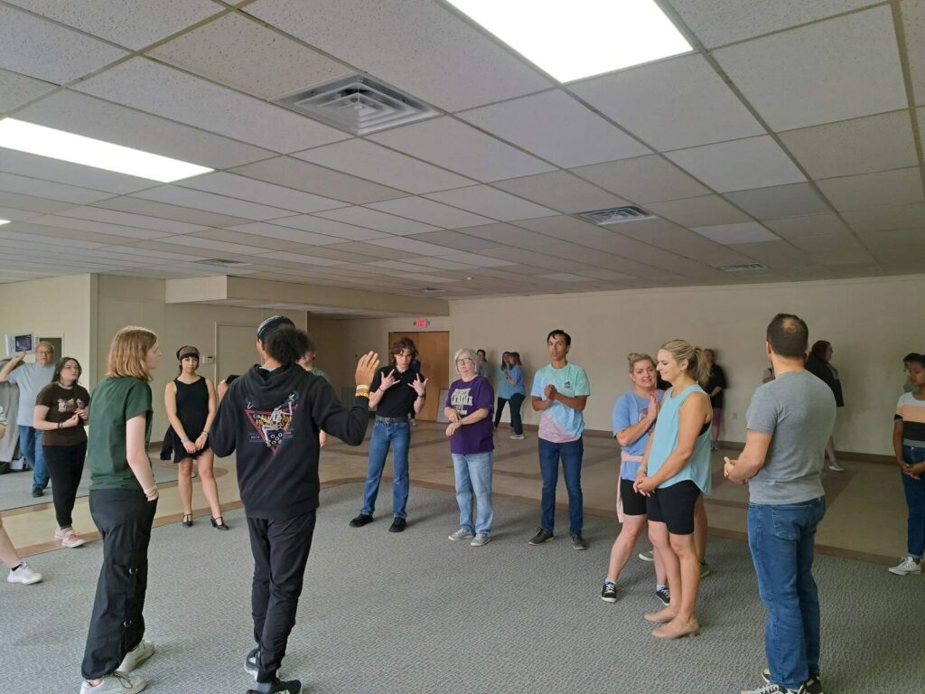 Performers listening to instruction while refining Gavotte choreography