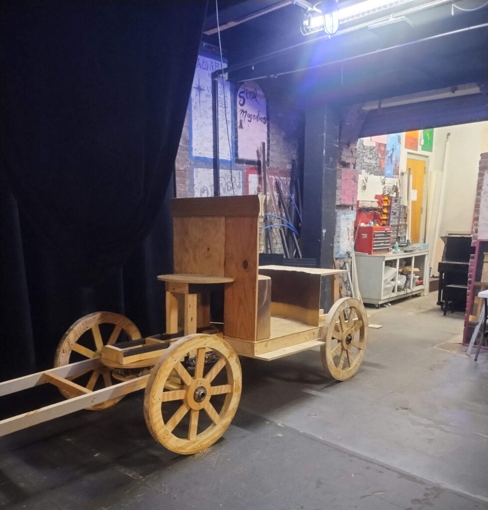 Wooden carriage in theater backstage area.