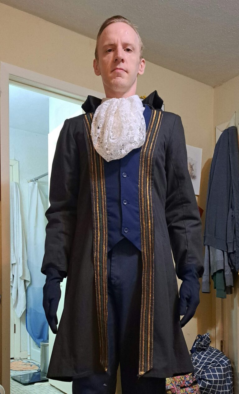 A man in a royal court costume with a lace jabot and dark embroidered coat.