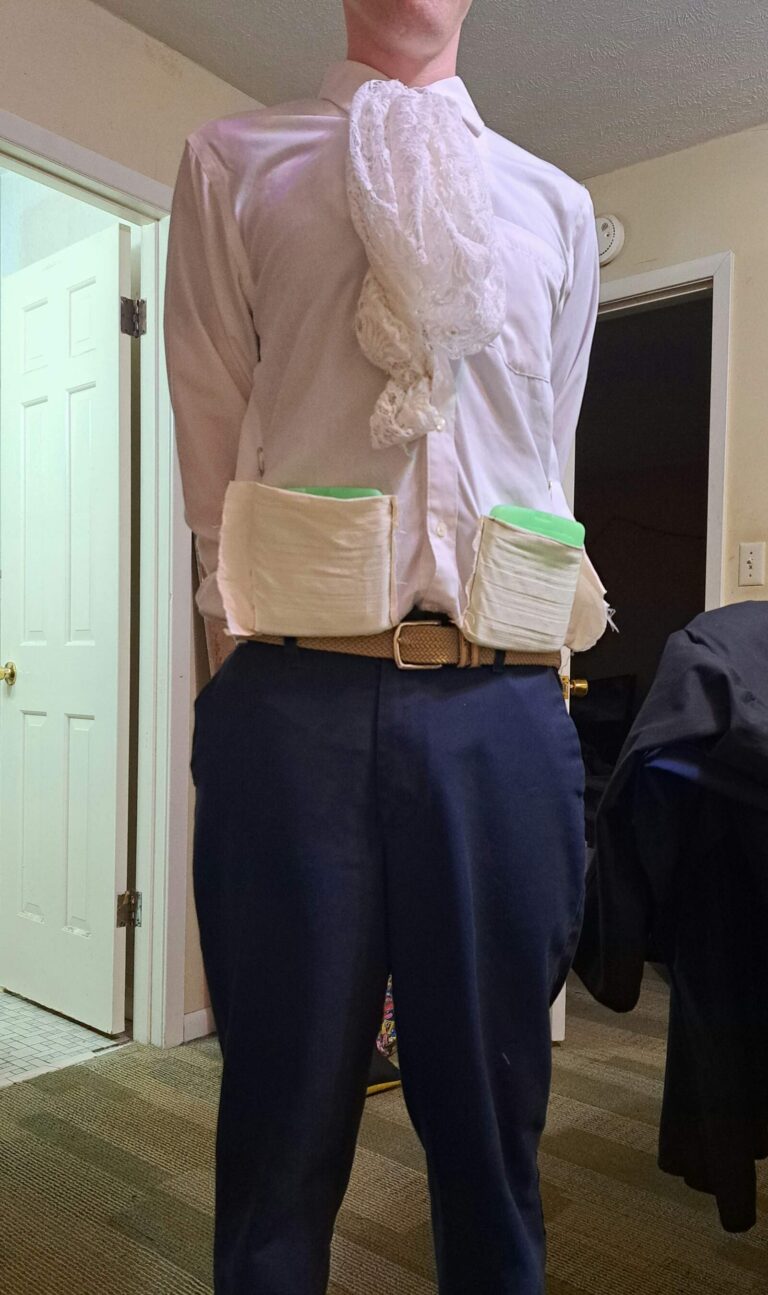 A man in a white shirt shows fabric pockets holding green cooling packs at his waist.
