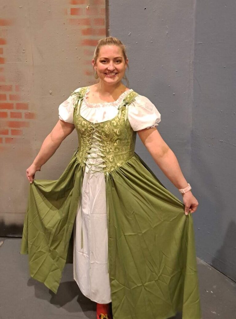 Actor Annina Nabors models green and cream townsperson dress against theater wall