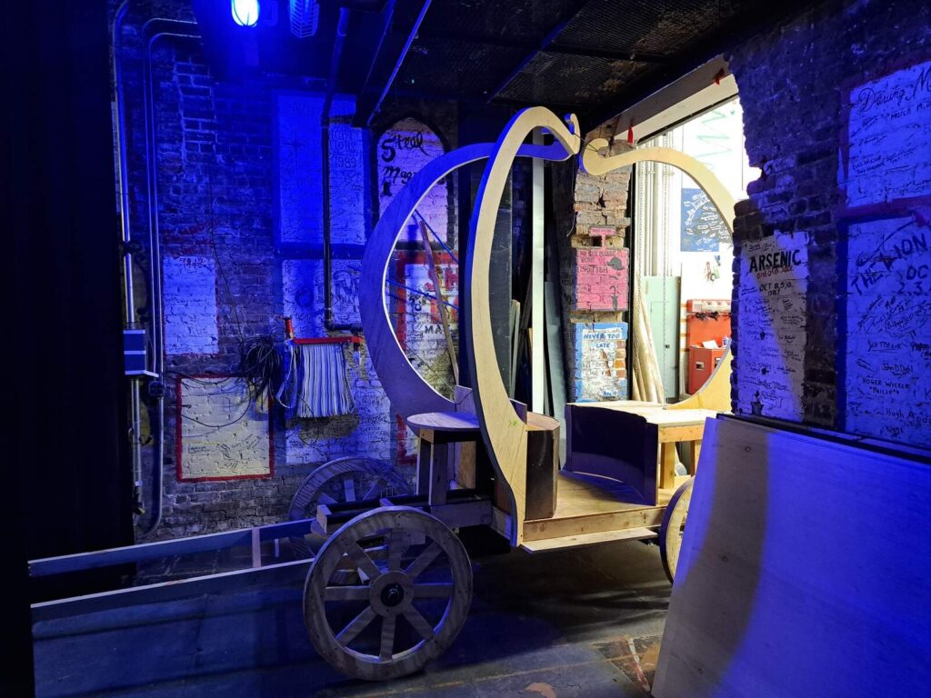 Unfinished wooden carriage frame illuminated by blue backstage lighting