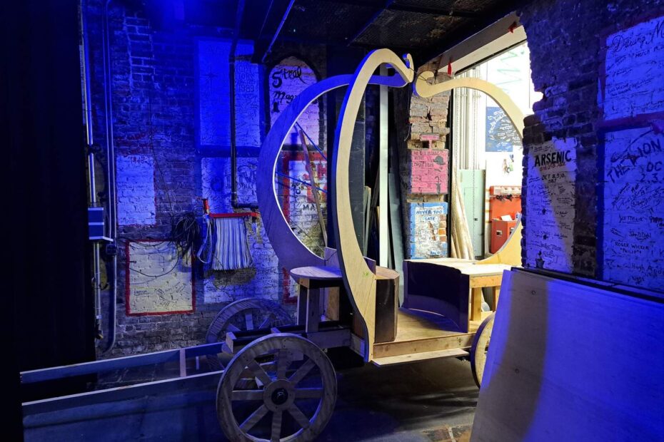 Unfinished wooden carriage frame illuminated by blue backstage lighting