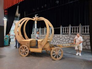 Chuck test-pulls the gold pumpkin-shaped carriage across the stage