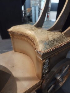 Close-up of damask-covered seat with beaded trim on the gold carriage