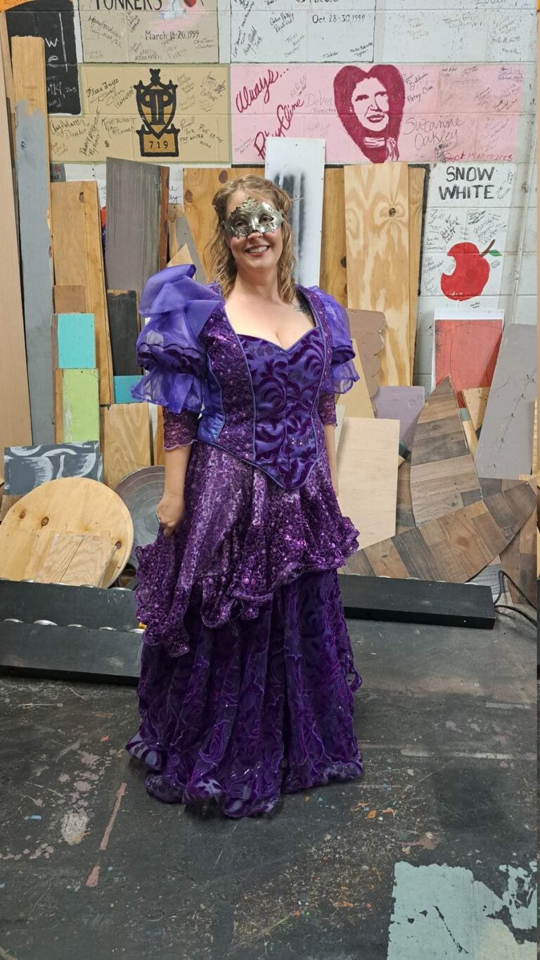 Performer in layered purple gown with silver mask