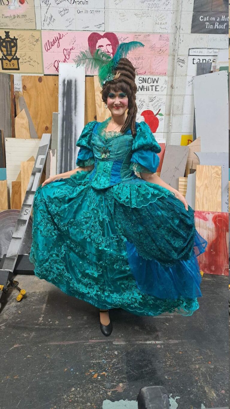 Full view of voluminous teal dress covered in beadwork and appliqués