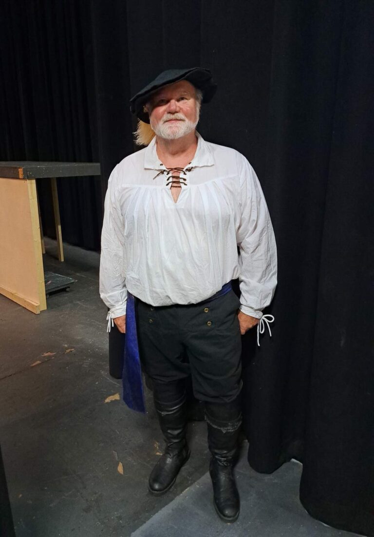 Cast member wears a white poet shirt, black breeches, tall boots, and felt hat during rehearsal