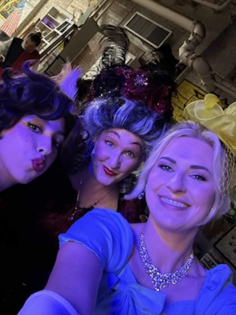 Playful selfie of three actresses in blue backstage lights.
