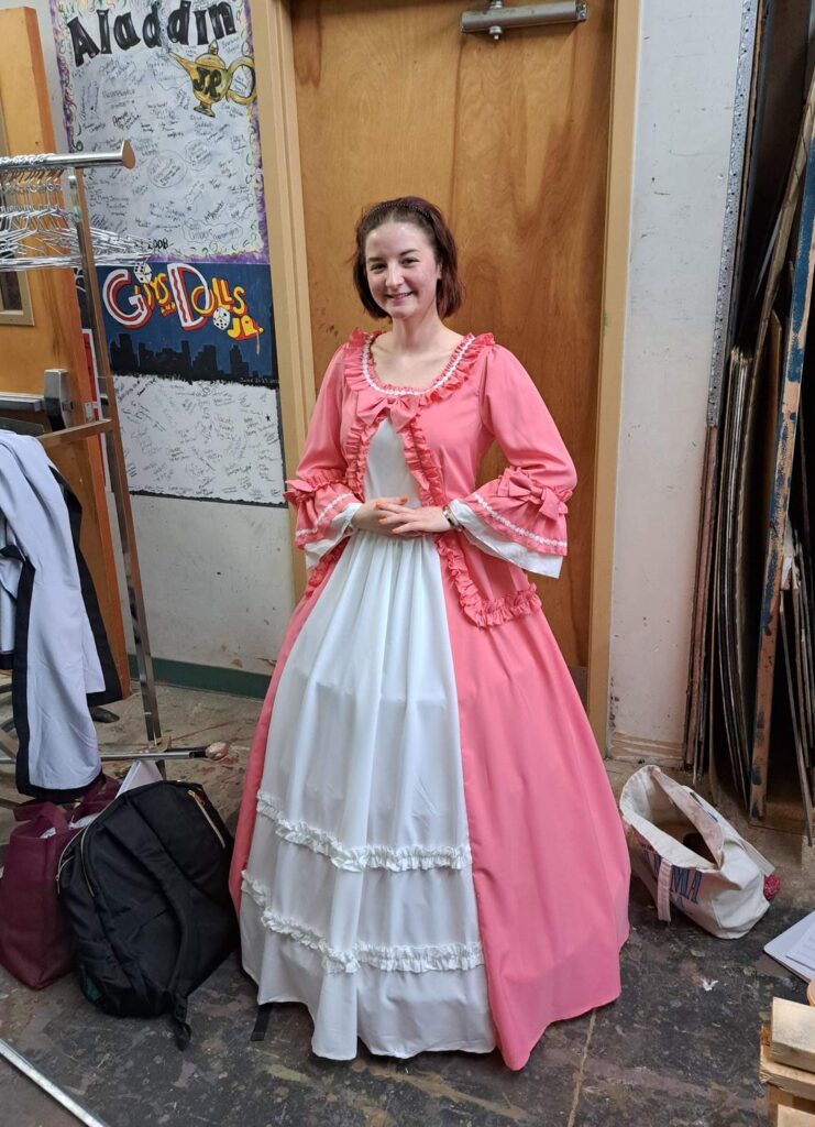 Performer wearing full-length pink and white ruffled ball gown