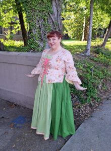 Period dress featuring pink-laced bodice and flowing green skirts.
