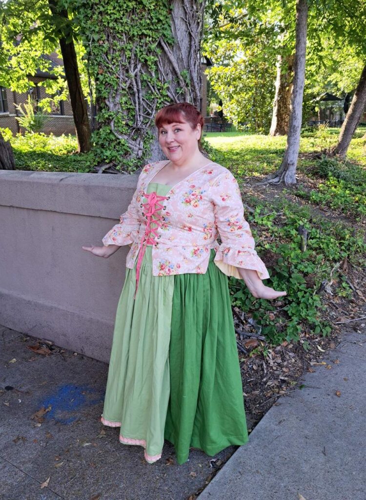 Period dress featuring pink-laced bodice and flowing green skirts.