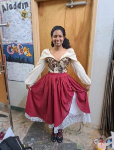 Performer with burgundy overskirt, lace hem underskirt, and floral corset